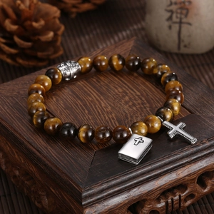 Detail of tiger eye bead bracelet with silver cross pendant on wooden stand