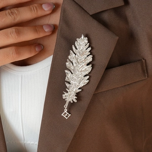 Detail of silver feather brooch with crystals on a brown blazer for retro fashion look