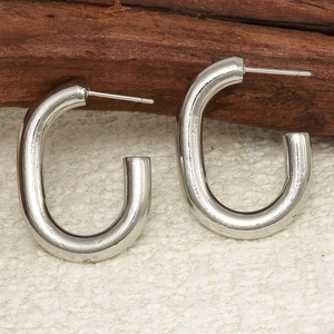 Close-up of sleek silver U-shaped stainless steel earrings on a natural wooden surface
