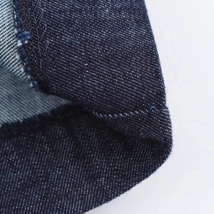 Gros plan du tissu denim bleu foncé montrant le sergé haute densité et les coutures
