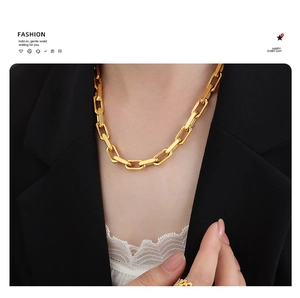 Detail of chunky gold paperclip link chain necklace worn on a model in a black blazer