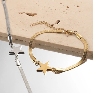 Elegant gold and silver star pendant snake chain bracelet on a textured stone background