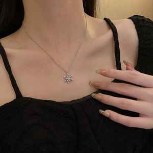 Close-up of sparkling silver snowflake pendant necklace worn on a model's collarbone