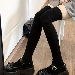 Close-up of black ribbed knit over-the-knee socks showing texture and stretch fit
