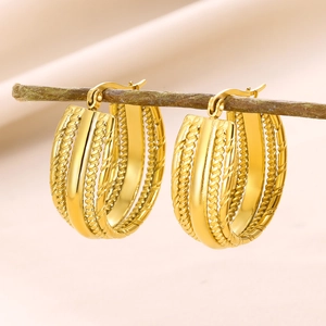 Detail view of gold layered hoop earrings with twisted and smooth texture on a wood stand