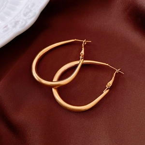 Close-up of gold-plated oval drop earrings featuring a matte brushed metallic finish
