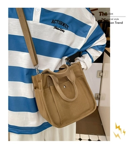 Detail of khaki canvas bag with adjustable wide strap and multi-pocket design