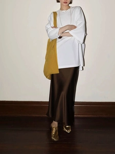 Women's oversized white batwing sleeve T-shirt with brown satin midi skirt and yellow bag