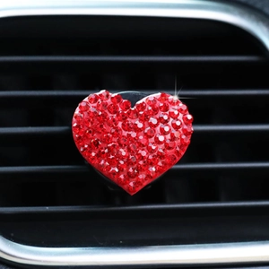 Macro detail of red rhinestone heart-shaped car air vent clip with sparkling crystals