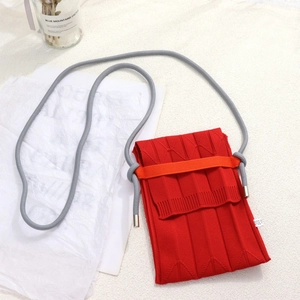Detail der roten gestrickten Handytasche mit orangefarbenem Akzent und grauem Schultergurt