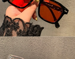 Detail view of square vintage sunglasses with black frames and orange lenses