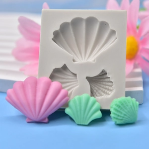 White silicone shell mold with pink and green seashell resin crafts on a blue background