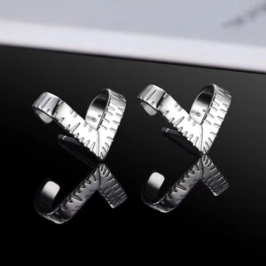 Macro shot of silver heart-shaped earring with S925 engraving on a black mirror surface