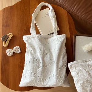 Close-up of white cotton floral embroidery and hollow-out lace texture on tote bag