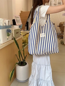 Vertical blue and beige striped seersucker tote bag for women in a cafe setting