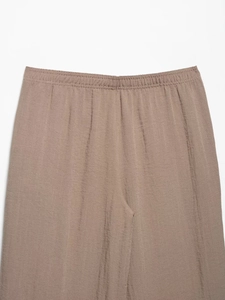 Dettaglio della vita elastica marrone e del tessuto stropicciato dei pantaloni a zampa