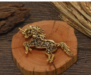 Detailed back view of a vintage unicorn metal brooch displayed on a rustic wood slice