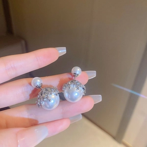 Detailed view of dual-sided pearl stud earrings with sparkling silver diamond caps