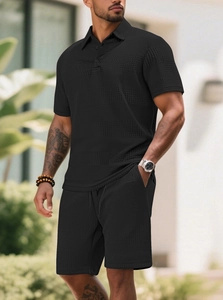 Detail of men's black knit polo shirt and shorts set featuring waffle texture fabric