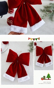 Detail of red velvet Christmas bow with plush white trim held in hand for holiday decor