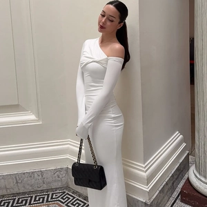 Détail de la robe blanche asymétrique montrant le drapé élégant et la texture du tissu