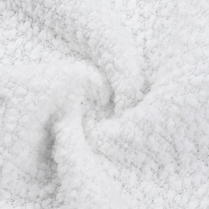 Close-up of white textured boucle fabric showing soft plush fleece material detail
