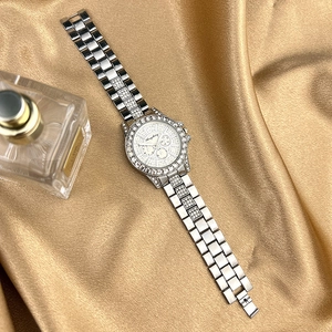 Detailed macro view of a silver rhinestone watch with three-eye dial on gold silk background
