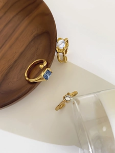 Detailed view of three gold irregular rings with blue, opal, and clear gemstones