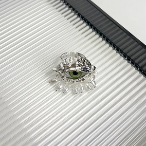 Detail of vintage evil eye ring with green accent and white pearl on silver metal