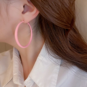 Close-up of model wearing matte pink twist heart hoop earrings in a stylish pose