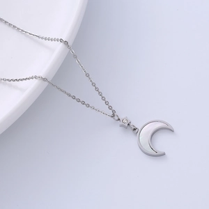 Silver celestial necklace with moon and star shell pendants on light gray background