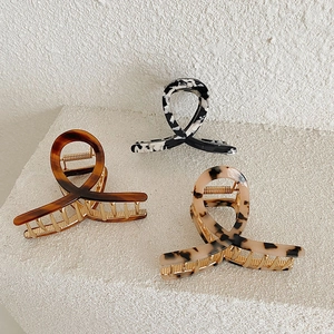 Detailed view of three acetate hair claws in tortoiseshell, leopard and floral patterns