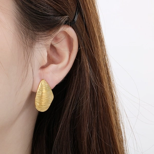 Elegant gold irregular water drop earrings with brushed texture on model in white setting