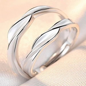 Close-up of adjustable silver couple rings with twisted wave design on soft fabric