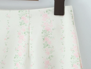 Détail du tissu tissé à fleurs avec roses roses et feuilles vertes sur jupe blanche