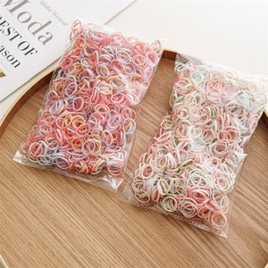 Macro detail of colorful elastic hair bands in a rustic wooden tray with pastel tones