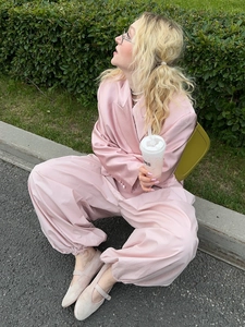 Detail view of pink satin loose fit trousers with smooth glossy texture and silky finish