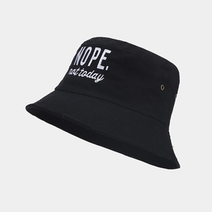 Detail of black cotton bucket hat featuring white NOPE embroidery and metal eyelets