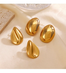 Detailed close-up of golden teardrop and pebble stud earrings on elegant textured background