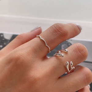 Detail of silver wavy line ring and liquid metal style adjustable open ring on model