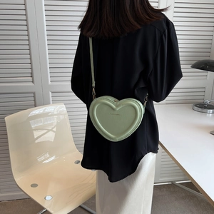 Vista posteriore di una modella con borsa a tracolla verde chiaro a forma di cuore