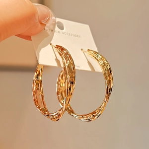 Close-up of elegant gold textured hoop earrings on a fashion display card