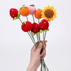 Handmade crochet bouquet with strawberry, persimmon and sunflower held against white background