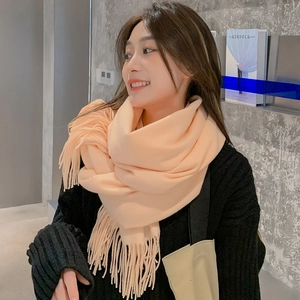 Close-up of soft beige tassel scarf worn by model in a cozy lifestyle setting