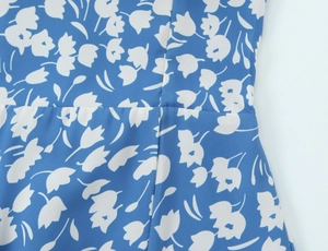 Détail de la couture à la taille sur cette robe bleue à imprimé de petites fleurs blanches