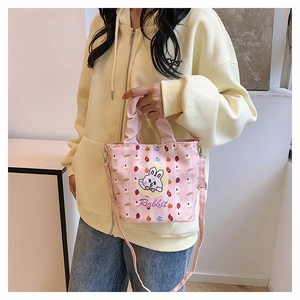 Detail of cute pink striped canvas bucket bag featuring cartoon rabbit and adjustable strap