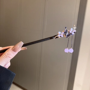 Detail of wooden hair stick with purple flower butterfly ornaments and beaded tassels