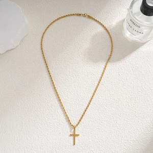 Gold stainless steel cross pendant necklace with rope chain on a textured background