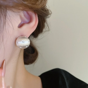 Close-up of star-embedded white pearl stud earring worn on a model's ear lobe