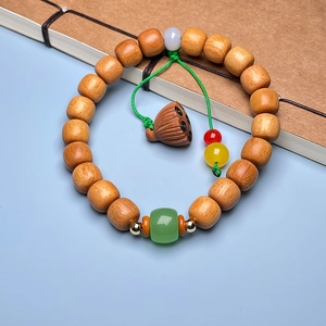 Detail of sandalwood bamboo-style bead bracelet with a lotus seed pod charm and green accent